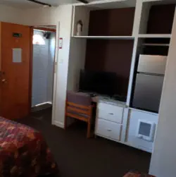 hotel room with desk, tv and mini fridge