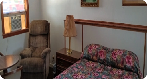 motel room with bed, lounge chair and AC