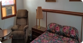 motel room with bed, lounge chair and AC