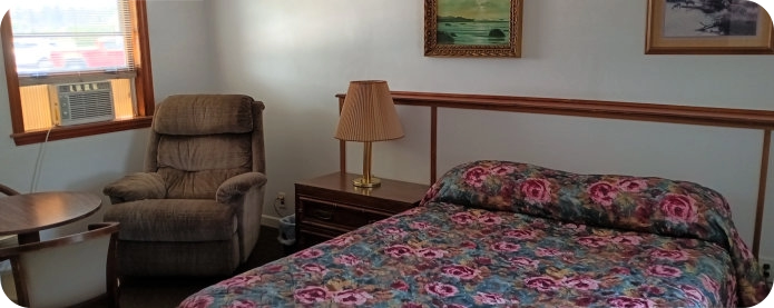 motel room with bed, lounge chair and AC